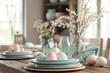 © tynza - Easter table in a modern farmhouse style, with vintage-inspired plates, mason jars as vases, and pastel-colored eggs as part of the decor.