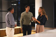 © Wavebreak Media - Diverse colleagues discussing project while using smartphone in modern office at night