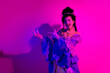 © deagreez - Elegant woman in royal princess costume posing under vibrant pink and purple neon lights