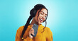 © peopleimages.com - Woman, headphones and phone for singing in studio, music subscription and karaoke on blue background. Online, streaming playlist sound and listening to track, happy and website for album on app
