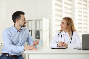 Wall Mural - Man having consultation with cardiologist at desk in clinic