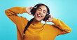 © peopleimages.com - Studio, woman and singing with headphones for music, motivation playlist and sweater for fashion. Smile, model and female person with audio equipment for listening, casual jumper and blue background