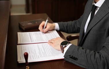 Wall Mural - Notary signing document at wooden table in office, closeup