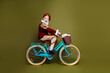 © deagreez - Senior man dressed as a nobleman riding a modern bicycle in costume against a khaki green backdrop