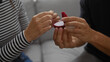 © Krakenimages.com - Woman and man holding an engagement ring box in a living room during a romantic moment
