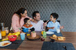 © Marcos - latin family with children having breakfast at home in Mexico Latin America, hispanic father and mother with son in domestic life