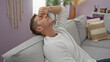 © Krakenimages.com - Young man looking stressed sitting on sofa in cozy living room, showcasing a modern home environment.