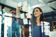 © peopleimages.com - Glass board, sticky notes and writing with business people in office together for brainstorming. Collaboration, meeting and training with colleague group in workplace for strategy discussion