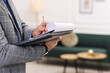 © New Africa - Real estate appraisal. Inspector with clipboard conducting property valuation indoors, closeup. Space for text