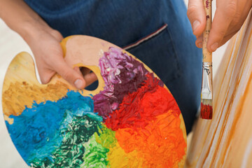 Wall Mural - Man with palette and paintbrush drawing picture, closeup