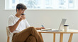 © Postmodern Studio - A man is sitting at a table with a laptop and a cup of coffee