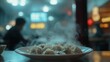 © Lush Diaries - Steaming plate of dumplings sits on a table in a dimly lit restaurant. A person sits blurred in the background.