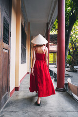 Wall Mural - back of a Vietnamese tourist woman in Non La hat at a pagoda temple in Vietnam on a trip to Asia