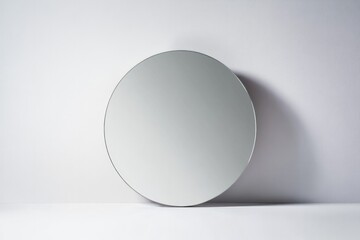 Wall Mural - round mirror with thin metallic frame reflecting soft light on clean white wall