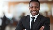 © Wilasinee - Confident Successful Businessman Smiling with Arms Folded in Blurred Corporate Office Background Conveying Professionalism Leadership and Positivity