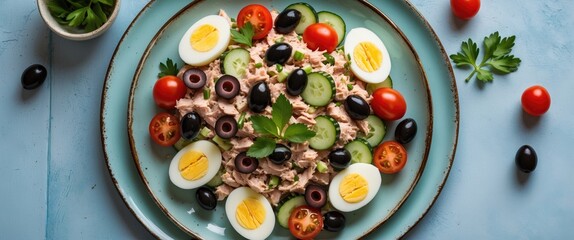 Wall Mural - Colorful tuna salad with cherry tomatoes, cucumber slices, black olives, and boiled eggs served on a turquoise plate with parsley garnish Copy Space