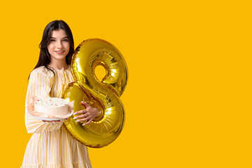 Wall Mural - Beautiful young woman with sweet bento cake and air balloon in shape of figure 8 on yellow background. International Women's Day