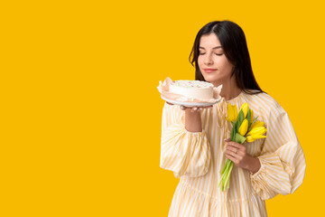 Wall Mural - Young woman with sweet bento cake and beautiful tulips on yellow background. International Women's Day