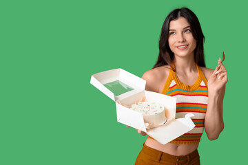 Wall Mural - Beautiful young woman holding box with sweet bento cake on green background. International Women's Day