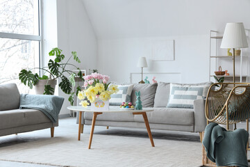 Wall Mural - Interior of modern living room with flowers, Easter eggs and greeting card on coffee table