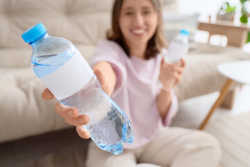 Wall Mural - Young woman with bottles of water at home