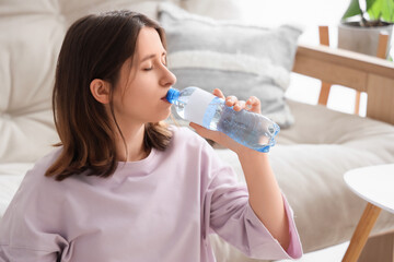 Wall Mural - Young woman drinking water  at home