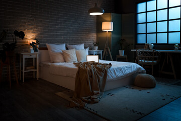 Wall Mural - Interior of bedroom with laptop on bed and glowing lamps at night