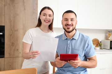 Wall Mural - Young couple with refund form and calculator in kitchen