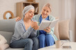 © Pixel-Shot - Young woman after chemotherapy with tea cup and nurse reading book on sofa at home. Brain cancer concept