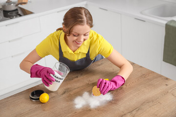 Wall Mural - Young woman with baking soda and lemon cleaning table in kitchen