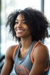 © felix_brönnimann - Smiling woman with curly hair in activewear at the gym enjoying workout routine, fitness motivation, healthy lifestyle, strength training, wellness journey.