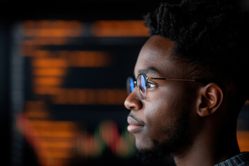 Wall Mural - Young man in glasses observing data on screen with focused expression