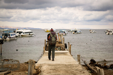 backpacker traveler standing on the pier of copacabana bolivia admiring the vast beauty of lake titi