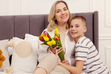 Canvas Print - Happy Mother's Day. Son greeting his mom with flowers at home