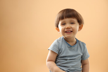 Wall Mural - Portrait of smiling little boy on beige background. Space for text