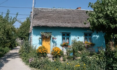 Picturesque Blue House with Thatched Roof and Flower Garden