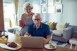 © Davor - Happy senior couple using laptop at home during breakfast
