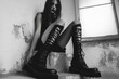 © Michael - Stylish woman showcasing trendy high black boots in a grunge, urban setting