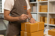 © Somdetmeaow - A man in apron is writing on a box with a pen. The box is stacked on top of another box