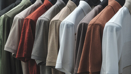 Poster - A row of shirts hanging on a rack, with the colors ranging from white to brown. The shirts are neatly folded and arranged in a row, creating a sense of order and organization