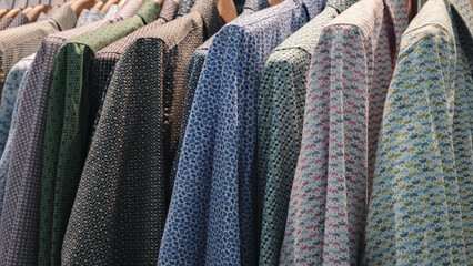 Poster - A rack of clothes with a variety of colors and patterns is displayed. The clothes are hanging on a rack, and the colors and patterns are diverse, ranging from solid colors to intricate designs