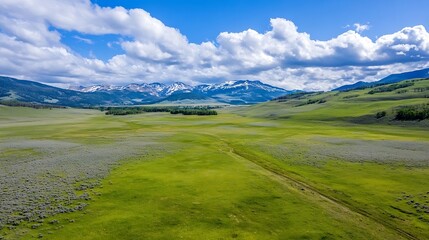 Wall Mural - Stunning aerial view of a vast green landscape with mountains and clouds in a clear blue sky : Generative AI