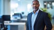 © Daiki - A confident middle-aged African American man dressed in a suit stands in a modern office setting, exuding professionalism and a friendly demeanor.