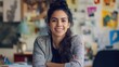 © Daiki - A young Hispanic female graphic designer smiles confidently in her creative workspace, showcasing her artistic flair and vibrant personality in a friendly atmosphere.