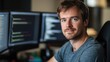 © Daiki - Portrait of a young European male software developer in casual attire, sitting in an office with multiple monitors. He exudes confidence and focus while working on coding projects.