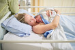 © peopleimages.com - Hospital, motherhood and woman with newborn, happy and love for baby on bed, labor or healthy. Clinic, hug and temperature regulation with skin contact, healthcare or new parent with care for infant