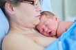 © peopleimages.com - Hospital, motherhood and woman with newborn, childbirth and love for baby on bed, labor and healthy. Clinic, healthcare and temperature regulation with skin contact, care and new parent with infant