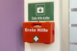 © InfiniteStudio - Red first aid kit mounted on a wall with clear health and safety signage in a well-lit environment