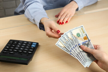 Wall Mural - Client giving dollar banknotes to cashier at table in money exchange, closeup