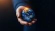 © Chanagun - A person's hand holding a small globe, symbolizing global responsibility and a connection to the Earth. The image highlights themes of sustainability and environmental awareness.